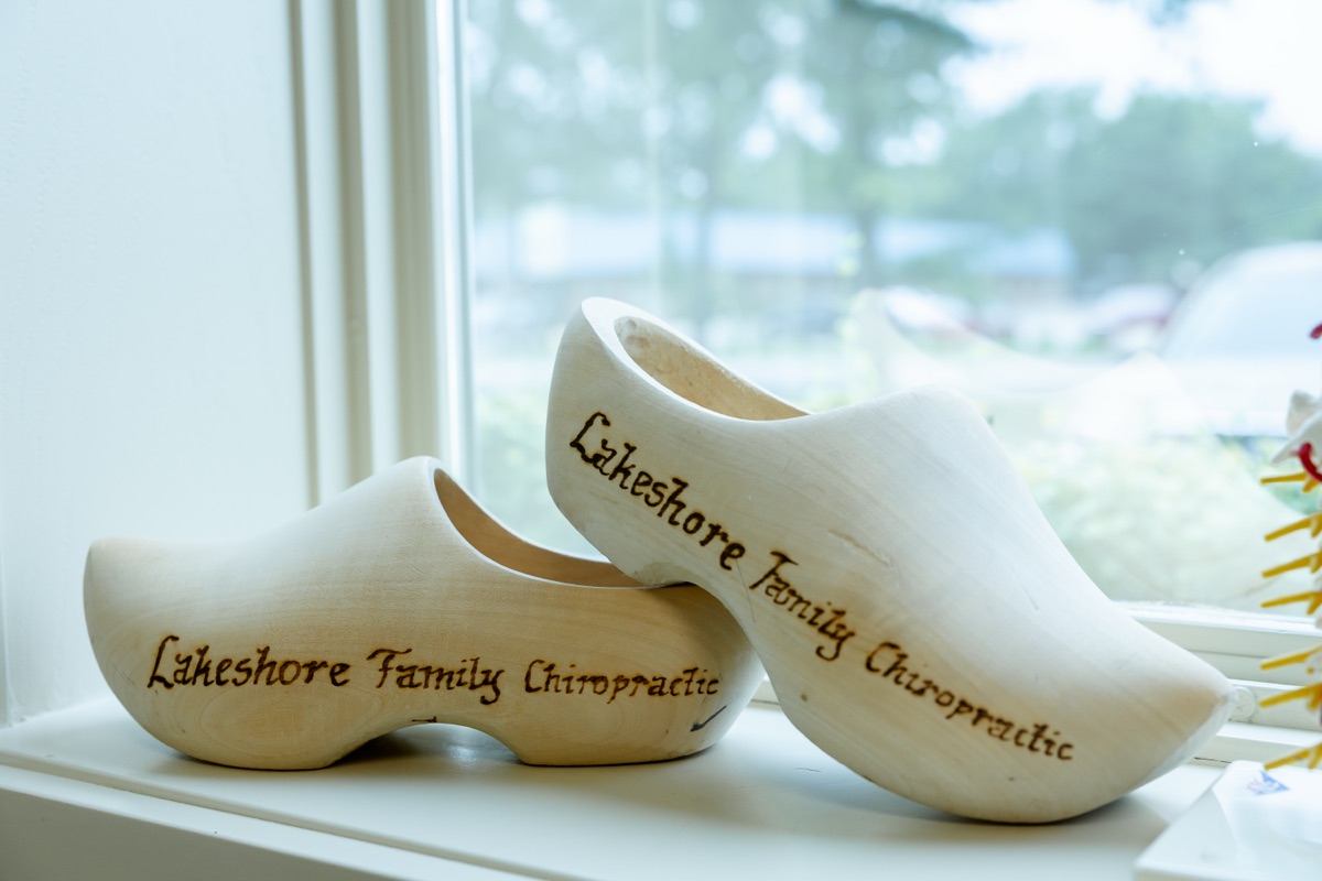 Engraved wooden shoes reading Lakeshore Family Chiropractic on a windowsill