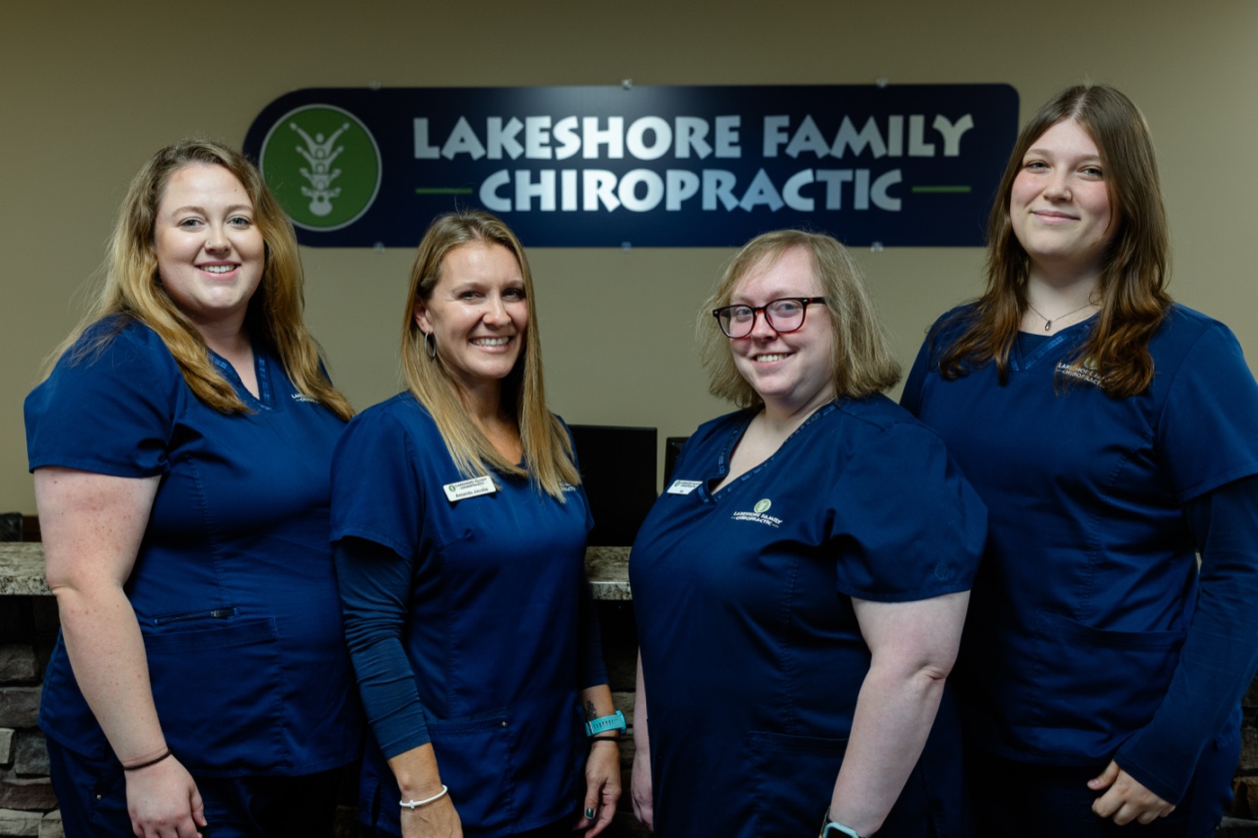 Members of the Lakeshore Family Chiropractic team beneath the practice sign
